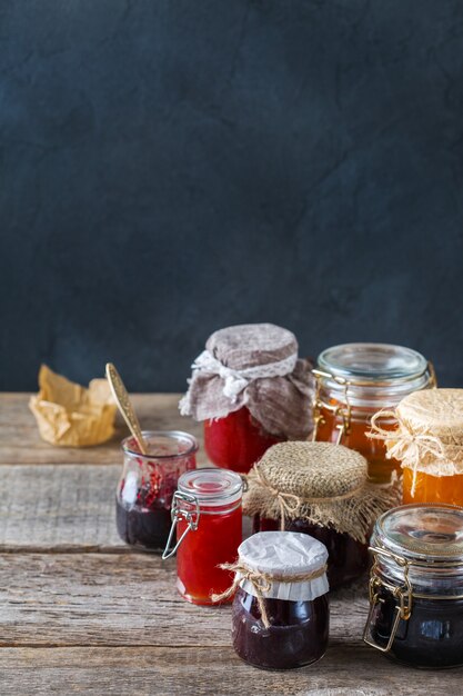 Eten en drinken, oogst zomer herfst concept. Assortiment van seizoensgebonden bessen en fruit jam in potten op een houten tafel. Ruimte rustieke achtergrond kopiëren