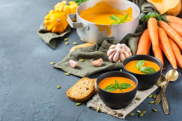 Eten en drinken stilleven dieet en voeding concept seizoensgebonden herfst herfst geroosterde oranje pompoen wortelsoep met ingrediënten op een rustieke houten tafel kopie ruimte gezellige keuken achtergrond