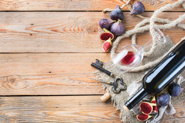 Eten en drinken stilleven vakantie seizoensgebonden oogsten val concept Fles kurkentrekker kurken glas rode wijn en vijgen op een rustieke houten tafel Kopieer ruimte achtergrond bovenaanzicht plat lag