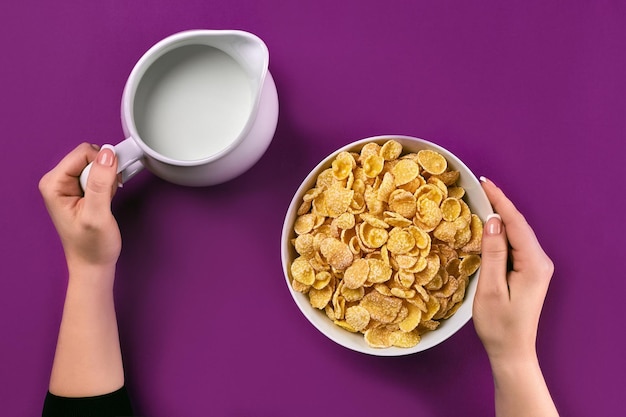 Eten en mensen concept handen van vrouw die granen cornflakes eet voor het ontbijt en melk giet