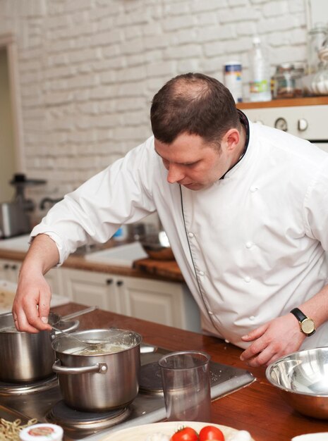 Eten en mensen concept mannelijke chef-kok met gekookt voedsel in de keuken