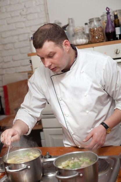 Eten en mensen concept mannelijke chef-kok met gekookt voedsel in de keuken