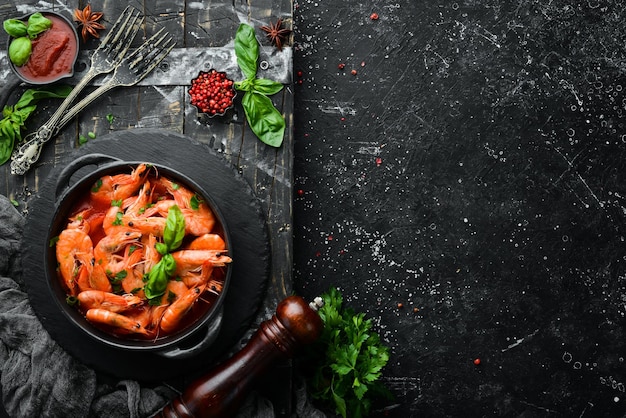 Eten Gekookte garnalen in tomatensaus met basilicum op een zwarte stenen plaat Bovenaanzicht Vrije ruimte voor uw tekst