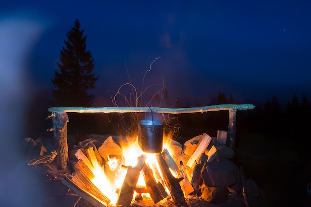 Eten koken in de pot in vuur en vlam onder de blauwe nachtelijke hemel met veel sterren