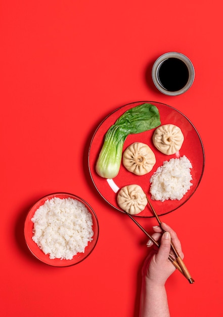 Eten met eetstokje Chinees gestoomd voedsel bovenaanzicht op een rode achtergrond