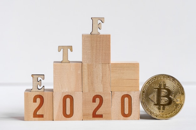 Etf letters made of wood next to a bitcoin coin. 