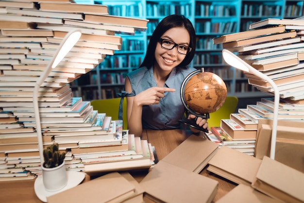 写真 民族のアジアの女の子は図書館で地球を使用しています