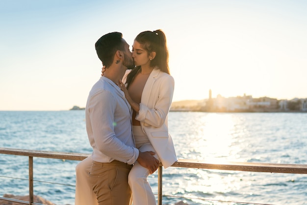 Ethnic couple in love kissing on sea embankment