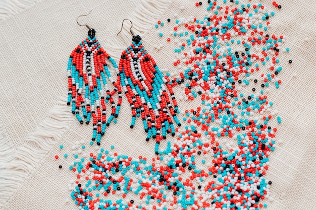 Ethnic decoration of an earring, visonane with a bead. Hand weaving beading, geometric pattern.