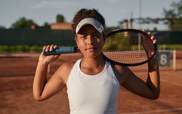 Ethnic sportswoman with tennis racket on court