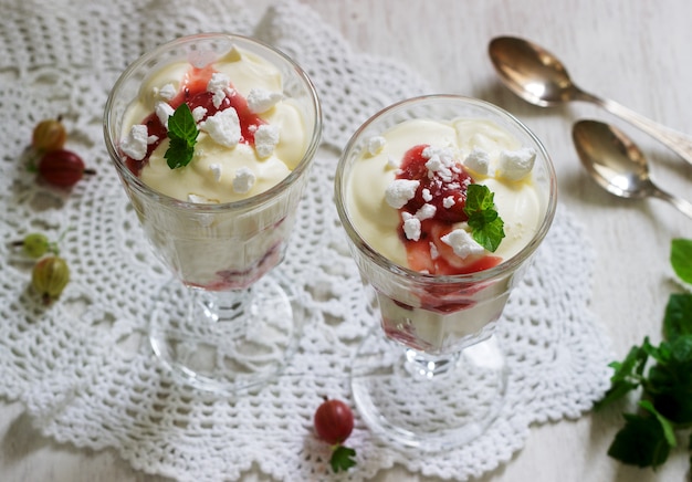 Foto pasticcio di eton, dessert inglese tradizionale con uva spina, panna montata e meringa su uno sfondo chiaro. stile rustico.