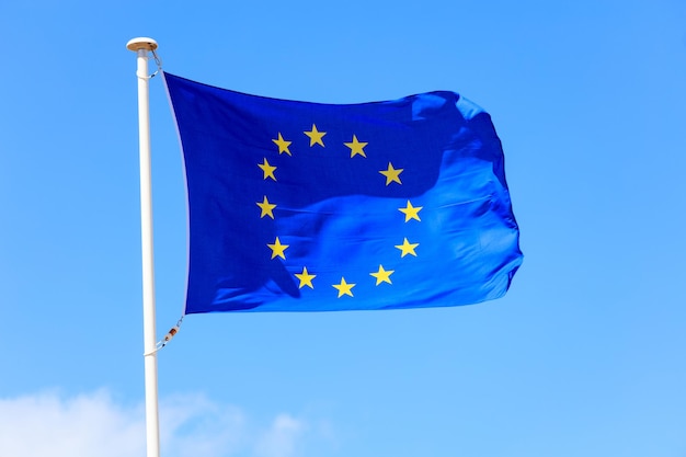 EU flag European Union flag on a pole waving on blue sky background