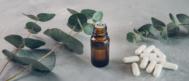 Eucalyptus etherische olie en verse bladeren, witte capsules pillen op het stenen bord.