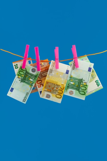 Euero money on rope clothespin on blue background