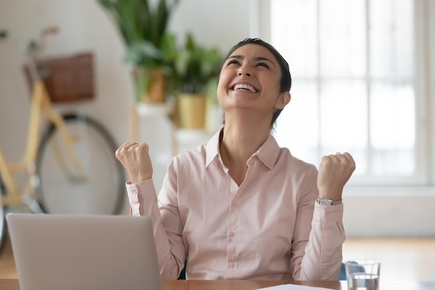 Euforische jonge Indiase zakenvrouw die ja-gebaar maakt en zich opgewonden voelt over professionele prestatie Gelukkige hindoe-vrouw die succes online loterij wint, goed nieuws op het werk