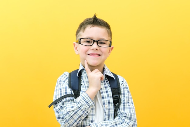 Eureka handsome little boy in glasses is surprised inspired i have an idea raise your index finger up copy space isolated on yellow background schoolboy