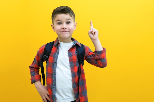 Eureka handsome little boy in glasses is surprised inspired i have an idea raise your index finger up copy space isolated on yellow background