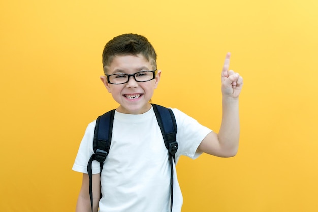 Eureka knappe kleine jongen in glazen is verrast geïnspireerd ik heb een idee steek je wijsvinger omhoog kopie ruimte geïsoleerd op gele achtergrond schooljongen