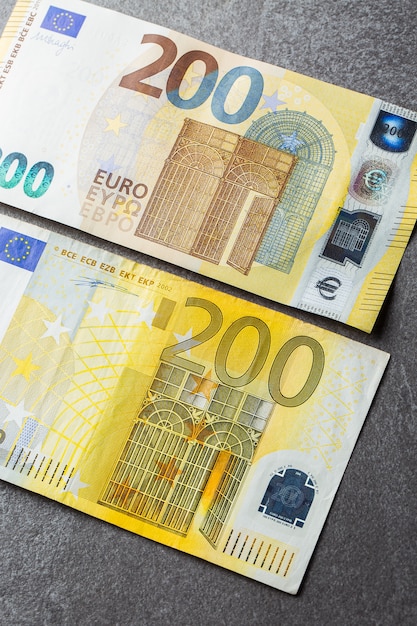Банкноты евро заделывают. Несколько двести евро банкнот на сером фоне 200 евро