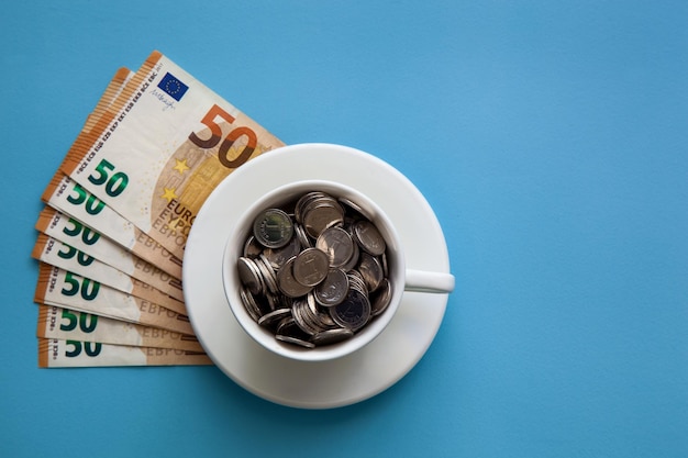 Euro banknotes and a cup