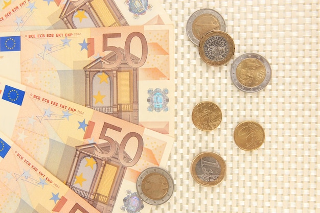 Euro banknotes and euro cents on beige background