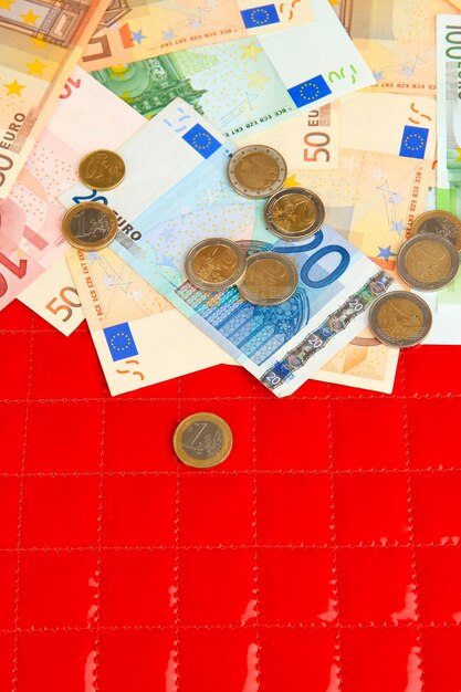 Euro banknotes and euro cents on red background