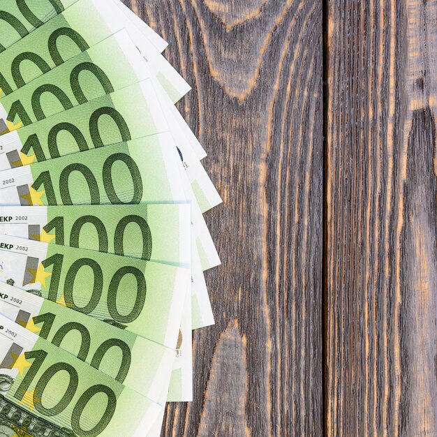 Euro banknotes in fan at wooden table.