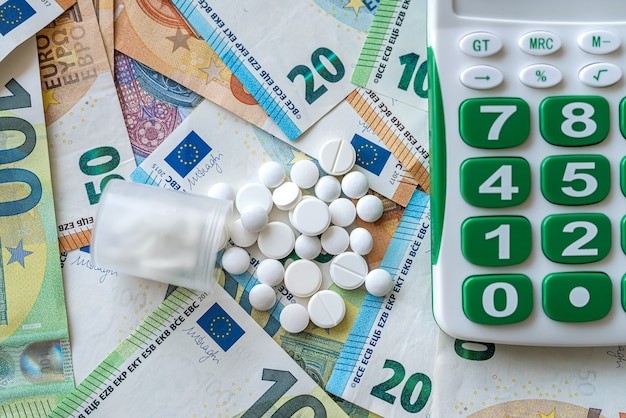 Euro banknotes money with calculator and capsule, medicine concept