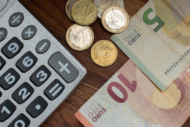 Euro banknotes and various coins around a calculator