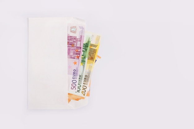 Euro banknotes in a white envelope on a white surface. Copy space.