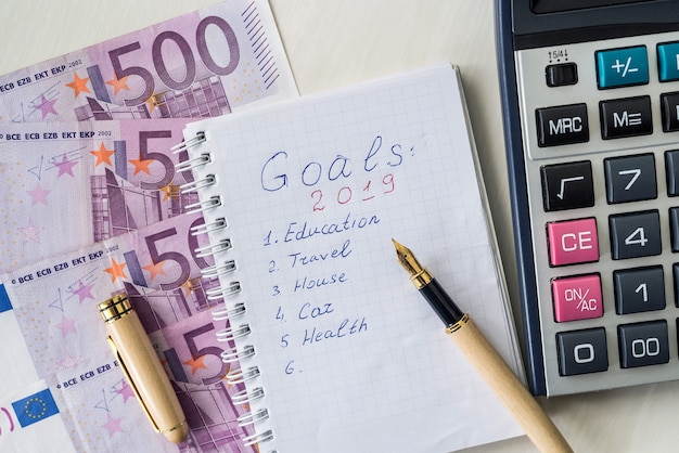 Euro banknotes with calculator and notepad with goals