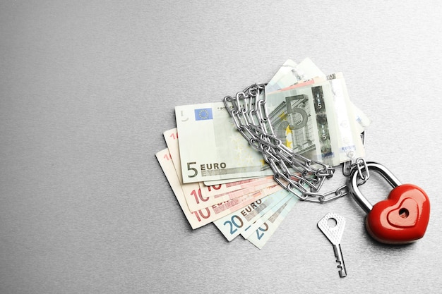 Euro banknotes with lock and chain on gray surface