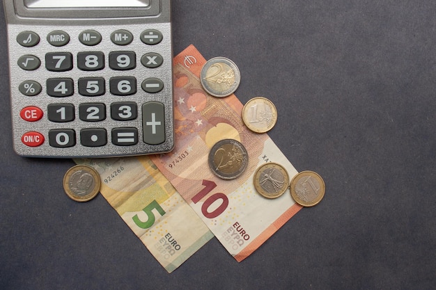 Euro bankntes and various coins around a calculator