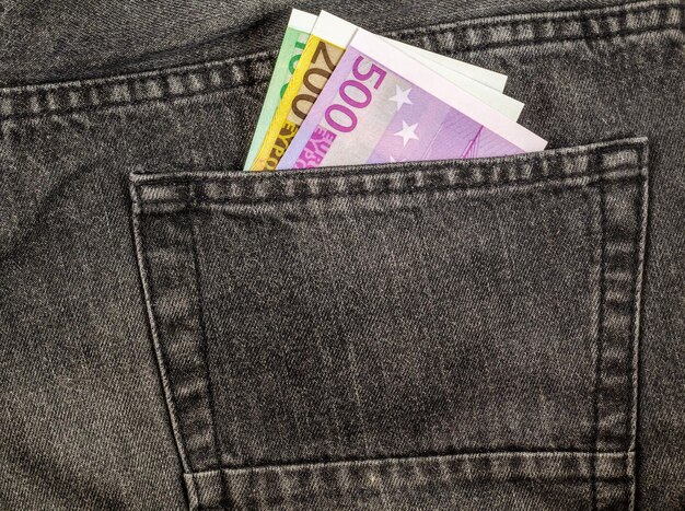 Euro biljetten van verschillende coupures in de achterzak van jeans.