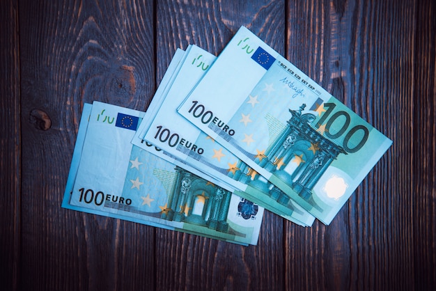 Euro cash banknotes on a dark wooden background.