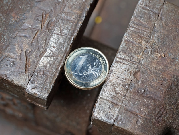 A Euro coin held in a metal grip