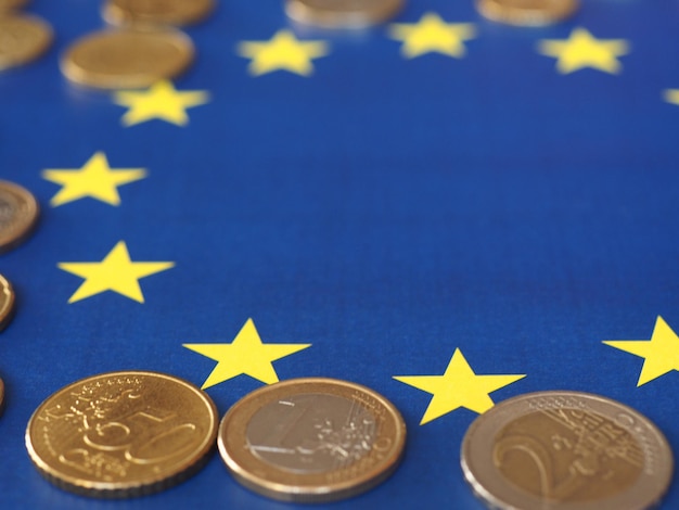 Euro coins (EUR), currency of European Union over flag of Europe