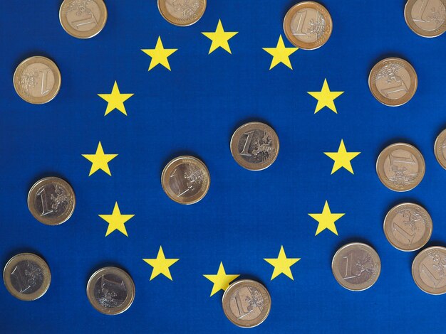 Foto monete in euro valuta eur dell'unione europea sopra la bandiera dell'europa