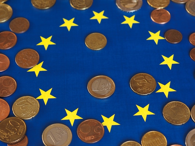 Foto euromunten (eur), munteenheid van de europese unie over de vlag van europa