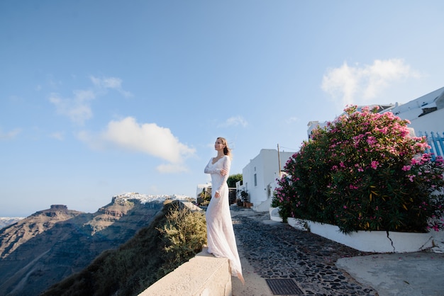 Europe Greece Santorini travel vacation. Woman looking at view on famous travel destination. Elegant young lady living fancy jetset lifestyle wearing dress on holidays. Amazing view of sea and Caldera