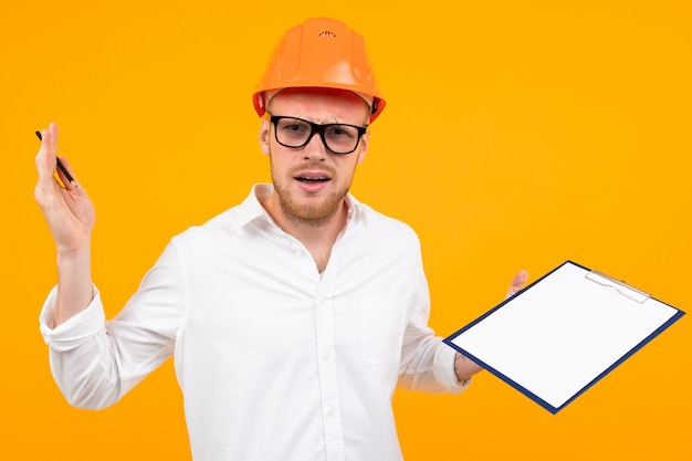 Photo european attractive guy in a classic white shirt and glasses in a construction helmet on yellow