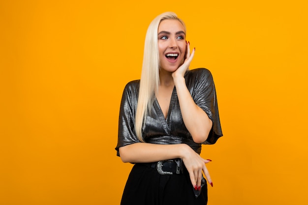 European blond girl model cute laughs on yellow wall