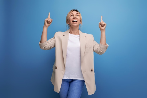 European blonde young adult woman pointing finger to side in studio