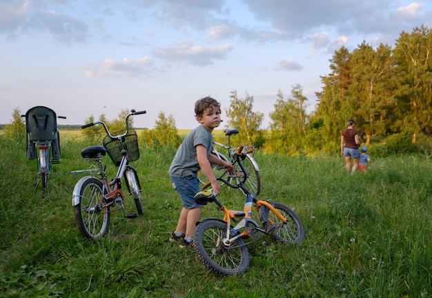 公園で夏に家族の自転車に乗っている間に自転車を持っているヨーロッパの少年