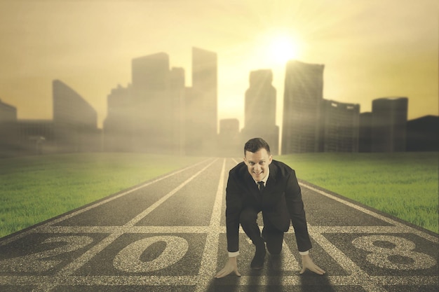 Photo european businessman kneeling above number 2018