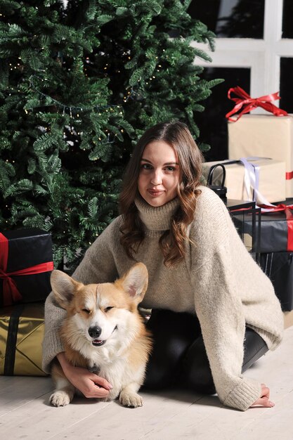 European caucasian young woman is sitting under a Christmas tree