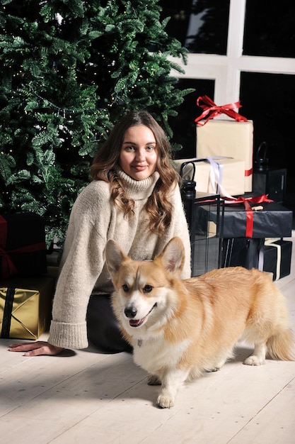 European caucasian young woman is sitting under a Christmas tree