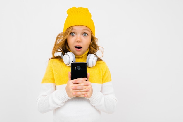Европейская милая девушка с большими наушниками и смартфоном слушает музыку и гримасы