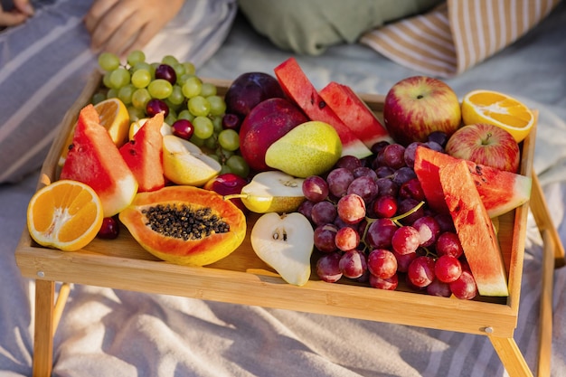 Foto famiglia europea si diverte a fare un picnic con frutta fresca e gustosa su un vassoio nel parco