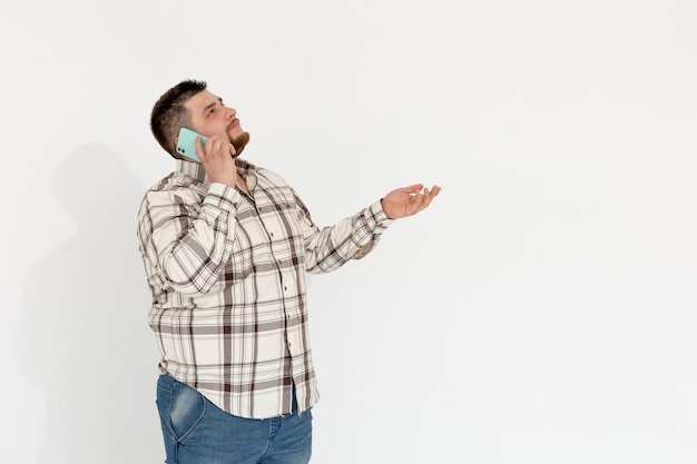 Европейский толстый эмоциональный молодой человек с телефоном на белом фоне